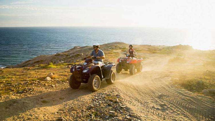 A pair kick up some dust on their ATVs.